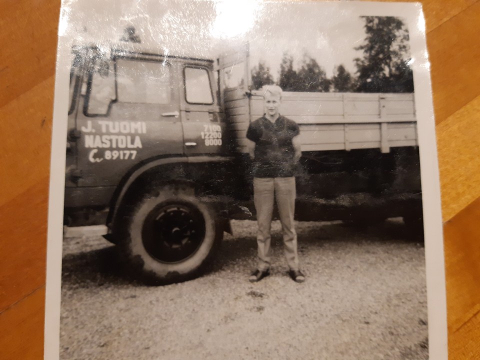 Vanha kuva miehestä kuljetusauton vieressä